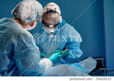 Surgeon and his assistant performing cosmetic surgery in hospital operating room. Surgeon in mask Surgeon and his assistant performing cosmetic surgery in hospital operating room. Surgeon in mask 50620525