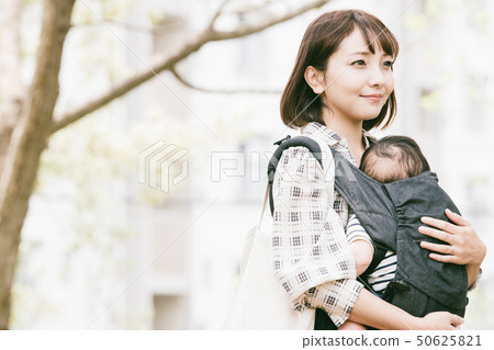 抱著嬰兒的母親新的綠色公園室外擁抱皮帶 50625821
