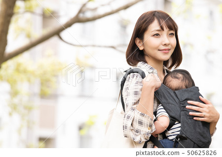 抱著嬰兒的母親新的綠色公園室外擁抱皮帶 50625826