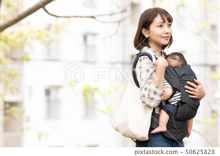抱著嬰兒的母親新的綠色公園室外擁抱皮帶 50625828