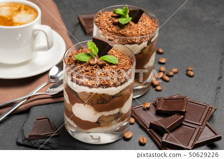 Classic tiramisu dessert in a glass and cup of coffee on dark concrete background Classic tiramisu dessert in a glass and cup of coffee on dark concrete background 50629226