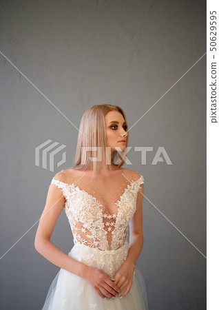 The bride in a white lace dress with embroidered bodice, indoors in loft style. Long,flowing, ash 50629595