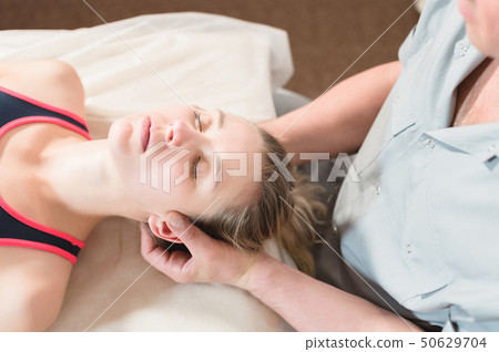 Male manual visceral therapist masseur treats a young female patient. Head and ear massage Male manual visceral therapist masseur treats a young female patient. Head and ear massage 50629704