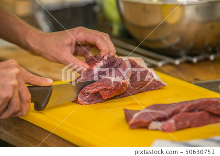 The chef prepares a raw beef steak for grilling The chef prepares a raw beef steak for grilling 50630751