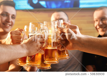 Selective focus of glasses of beer in hands of male friends Selective focus of glasses of beer in hands of male friends 50630930