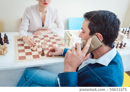 Business people playing chess with man on the phone 50631875