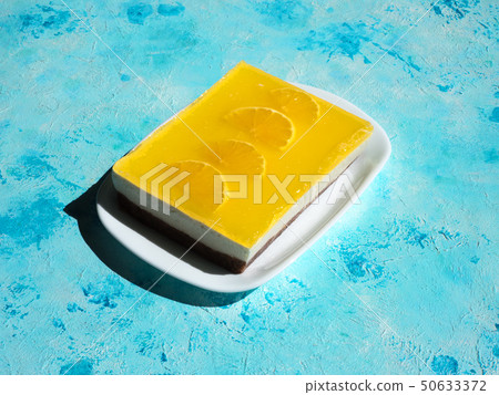 Yellow cheesecake on a sunny blue background. Yellow cheesecake on a sunny blue background. 50633372