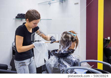 Professional hairdresser coloring hair of woman client at studio 50638924