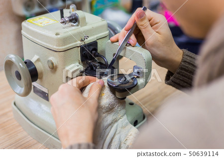 Skinner using sewing machine for stitching fur skin at atelier 50639114