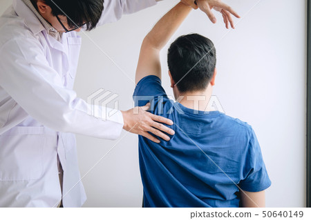 Doctor physiotherapist assisting a male patient 50640149