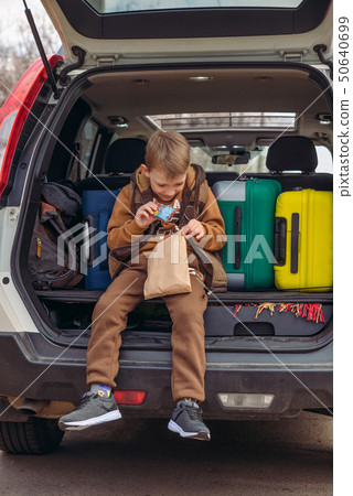 little kid looking into paper bag with candies sitting in car trunk little kid looking into paper bag with candies sitting in car trunk 50640699