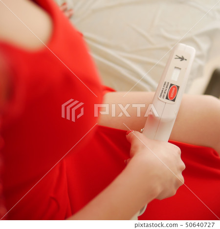 Beautiful young woman in a luxurious red dress makes herself laser hair removal in the spa salon 50640727