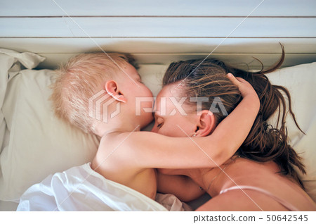 Toddler boy sleeping on pillow with mother 50642545
