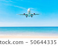 Plane on the blue sky is landing over the ocean 50644335