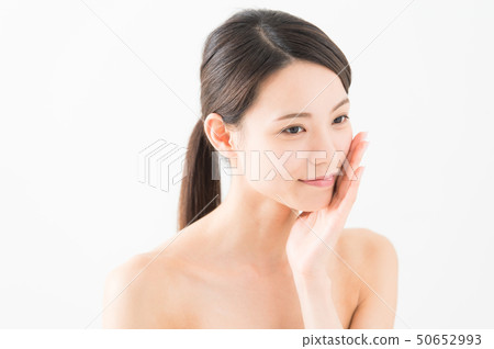 Image of a woman in her 20s moisturizing her cheeks Image of a woman in her 20s moisturizing her cheeks 50652993