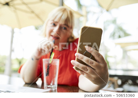 Woman photographing in outdoor cafe 50653360