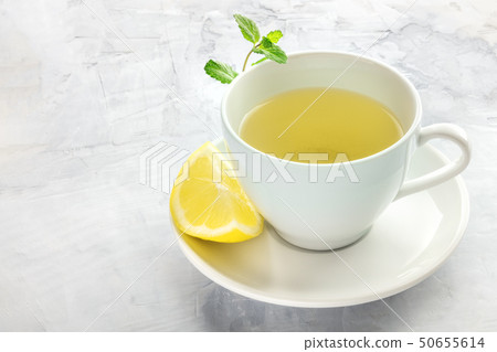 A cup of green tea with a wedge of lemon and mint leaves, with a place for text 50655614