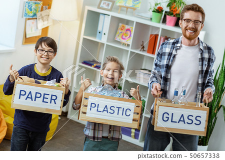 Beaming bearded teacher standing with his little students 50657338