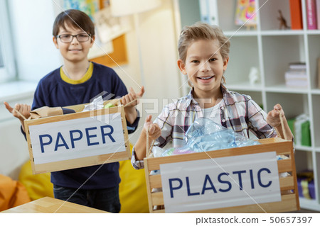 Happy diligent kids displaying mindful consumption while holding boxes 50657397