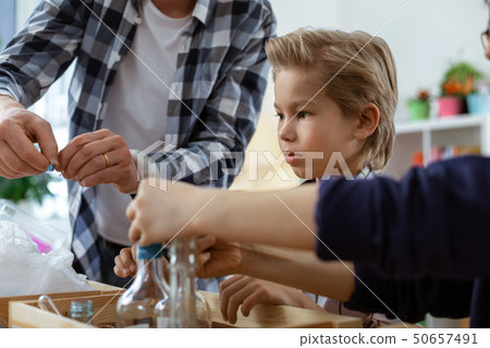 Smiling positive teacher in checkered shirt controlling his young nature lovers 50657491