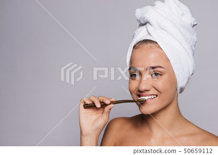 A portrait of young woman brushing teeth in a studio, beauty and skin care. 50659112