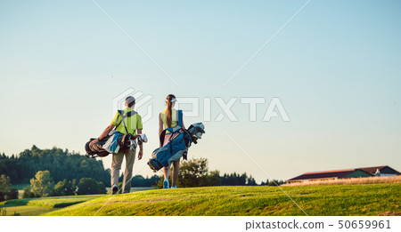 Happy couple carrying stand bags towards the golf course in a sunny day 50659961