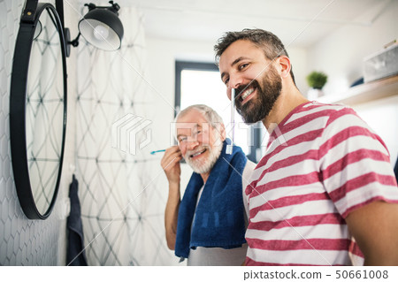 An adult hipster son and senior father in bathroom indoors at home, having fun. An adult hipster son and senior father in bathroom indoors at home, having fun. 50661008