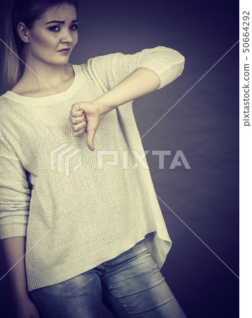 Sad woman showing thumb down gesture Sad woman showing thumb down gesture 50664292