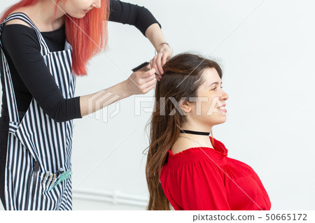 Hair Stylist, coloring and people concept - red hair hairdresser coloring young woman in red shirt Hair Stylist, coloring and people concept - red hair hairdresser coloring young woman in red shirt 50665172