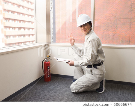 Worker checking fire extinguisher Worker checking fire extinguisher 50666674