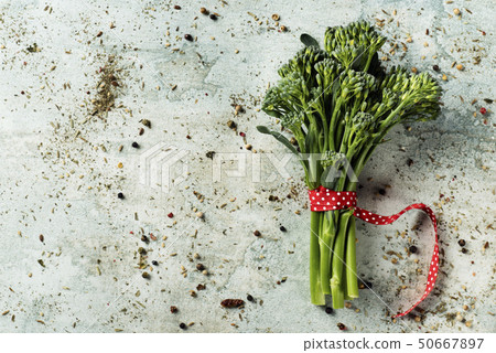 bunch of broccolini on a stone surface 50667897