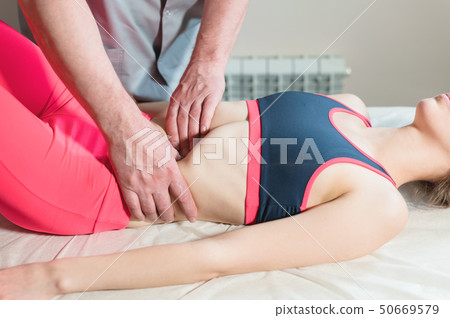 Male manual visceral therapist masseur treats a young female patient. Edit the internal organs and 50669579