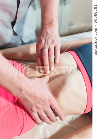 Male manual visceral therapist masseur treats a young female patient. Edit the internal organs and Male manual visceral therapist masseur treats a young female patient. Edit the internal organs and 50669581