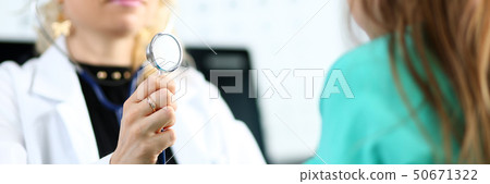 Blond mature gp hold stethoscope head in hand while diagnosing little girl Blond mature gp hold stethoscope head in hand while diagnosing little girl 50671322