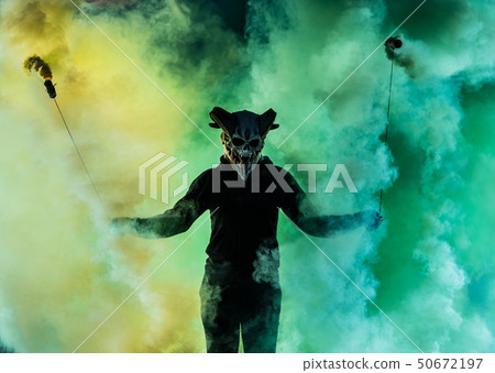 Devil with scary mask surrounded by coloured smoke Devil with scary mask surrounded by coloured smoke 50672197