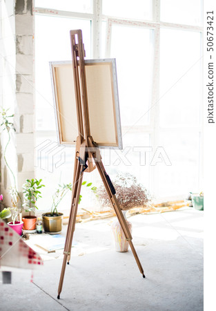 Easel with canvas standing in empty artistic studio Easel with canvas standing in empty artistic studio 50673421
