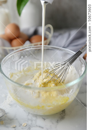 Mixing eggs, flour and milk in bowl. Mixing eggs, flour and milk in bowl. 50673603