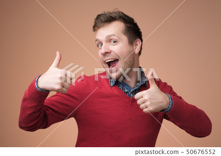 Happy handsome man in red sweater showing thumbs up Happy handsome man in red sweater showing thumbs up 50676552