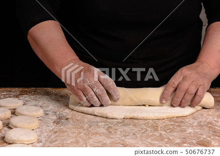 An elderly woman rolls out of a raw batter for 50676737