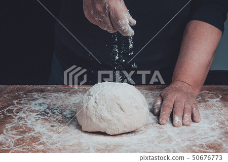 The hands of an old grandmother sprinkle with 50676773