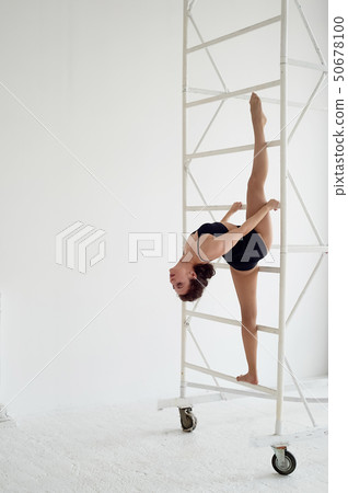 The splits in the air on metal poles.Gymnast in black tights. Flexibility 50678100