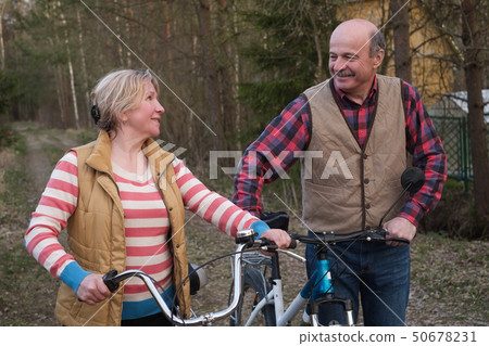 Happy elderly senior couple cycling in park 50678231