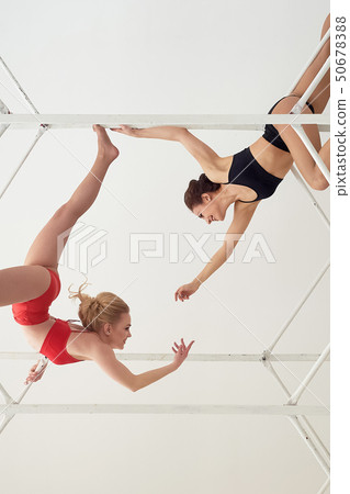 Gymnasts , pairs of poses. In red and black swimsuit on white background.Metal high construction 50678388