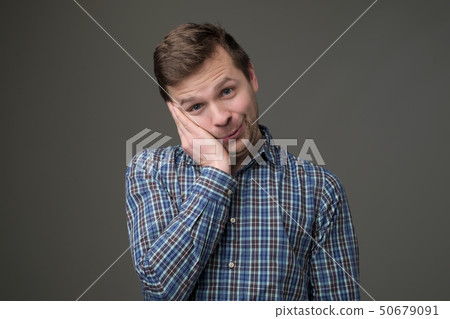 Smiling young caucasian man putting his hand to his chin 50679091