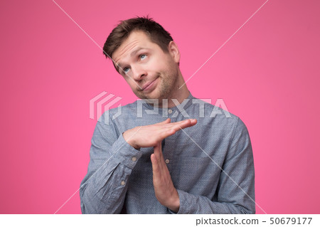 Young man giving showing time out with hands gesture isolated on pink background Young man giving showing time out with hands gesture isolated on pink background 50679177