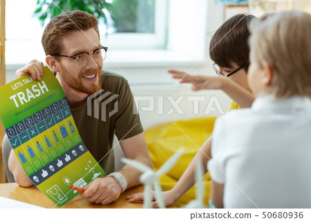 Cheerful bearded teacher presenting informative green poster 50680936