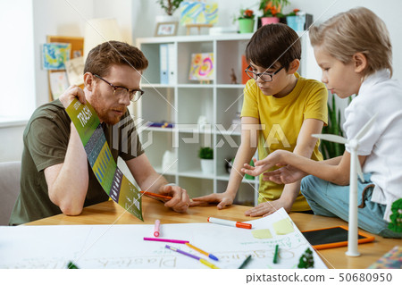 Attentive smart man pointing on the elements on educative poster 50680950