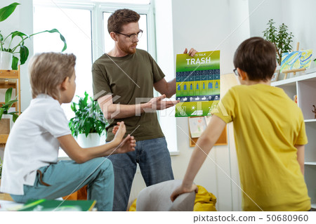 Active ginger teacher in blue jeans standing in front of his students 50680960