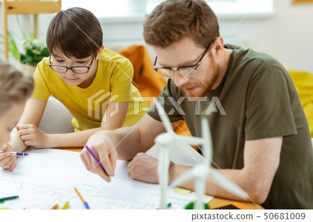 Concentrated teacher in clear glasses carrying colorful pencils 50681009