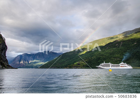 Sailing ship on a Norway fjord with mountains behind and rainbow and clouds above 50683836